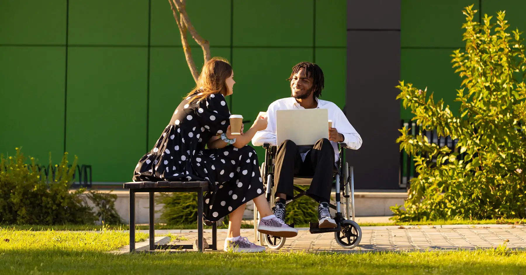Photo of a student in a wheelchair working in Anthology Ally next to an instructor sitting on a bench