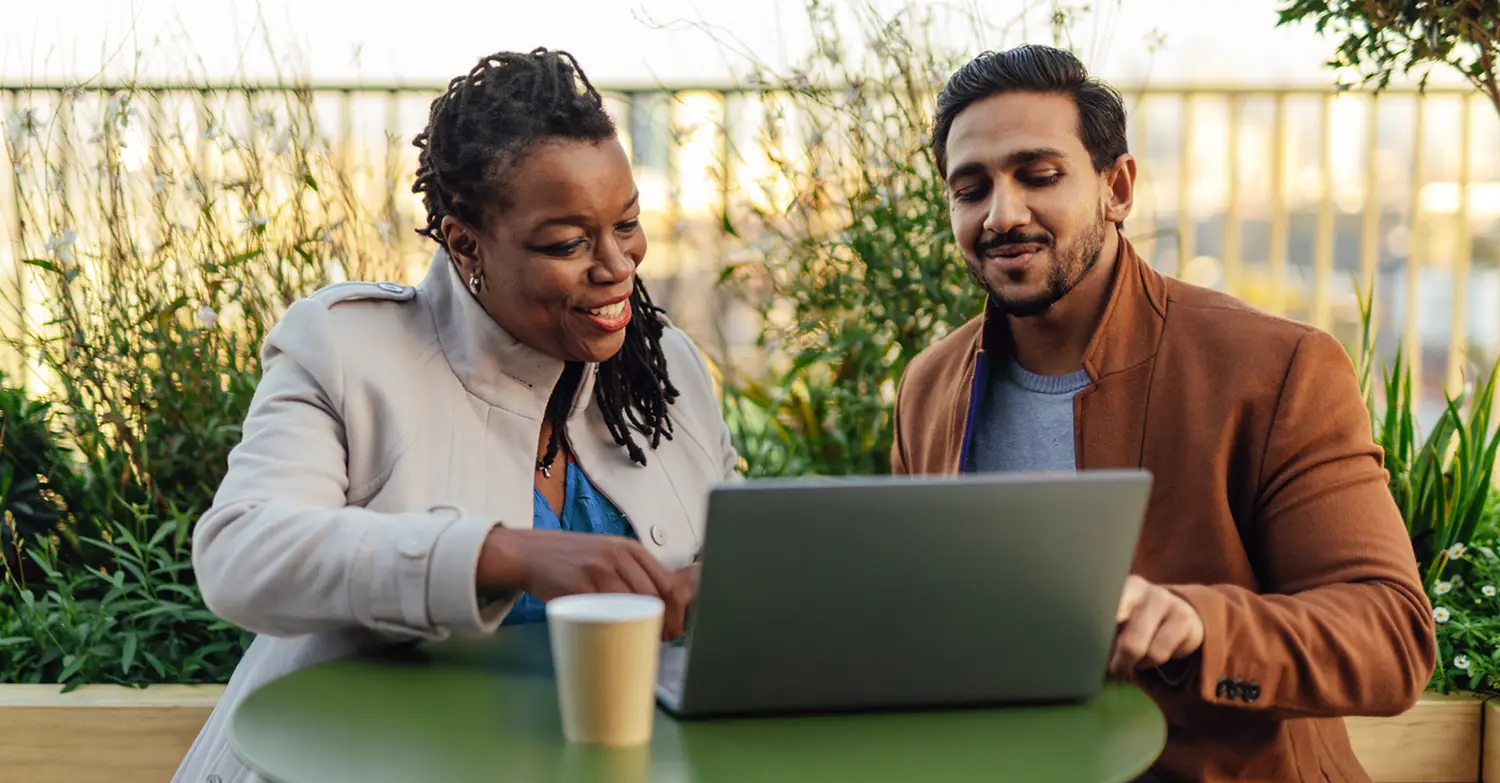 Photo of two people sitting outside and using Blackboard on a laptop
