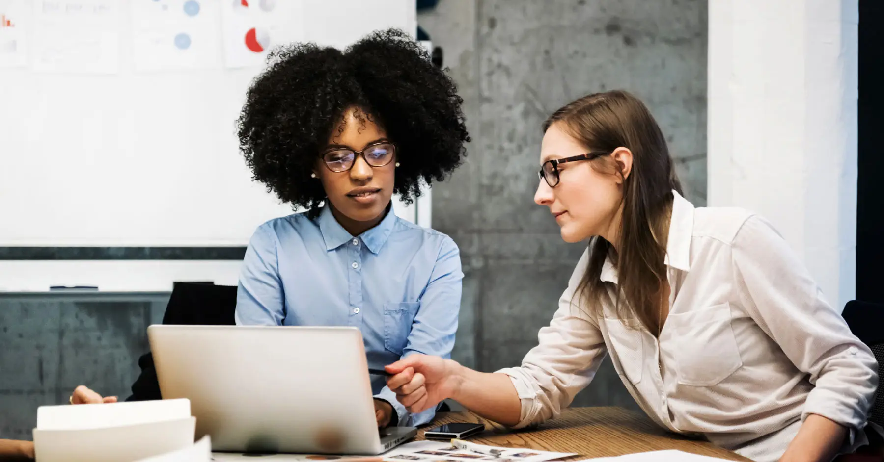 Two women working at a laptop making accessibility updates using Blackboard Ally