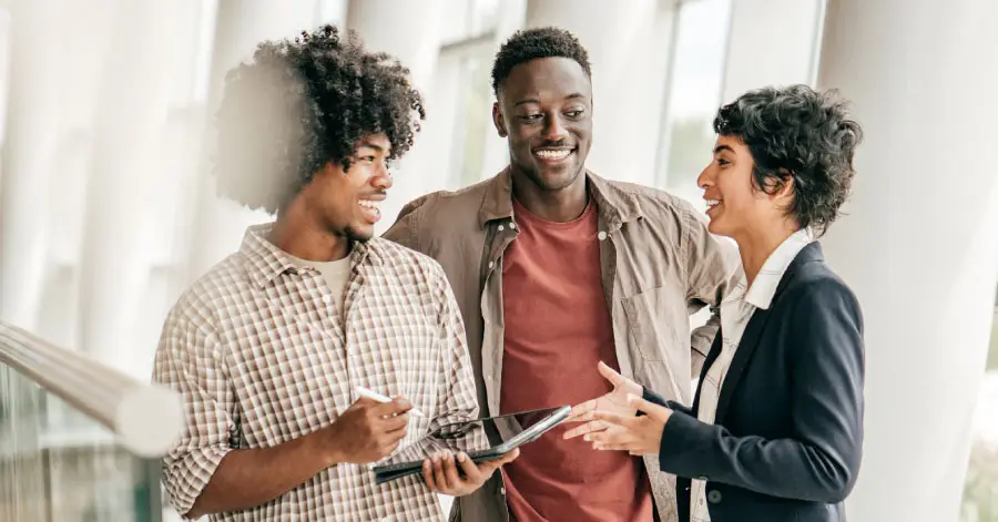 Photo of three students standing around a tablet looking at a course in Blackboard LMS