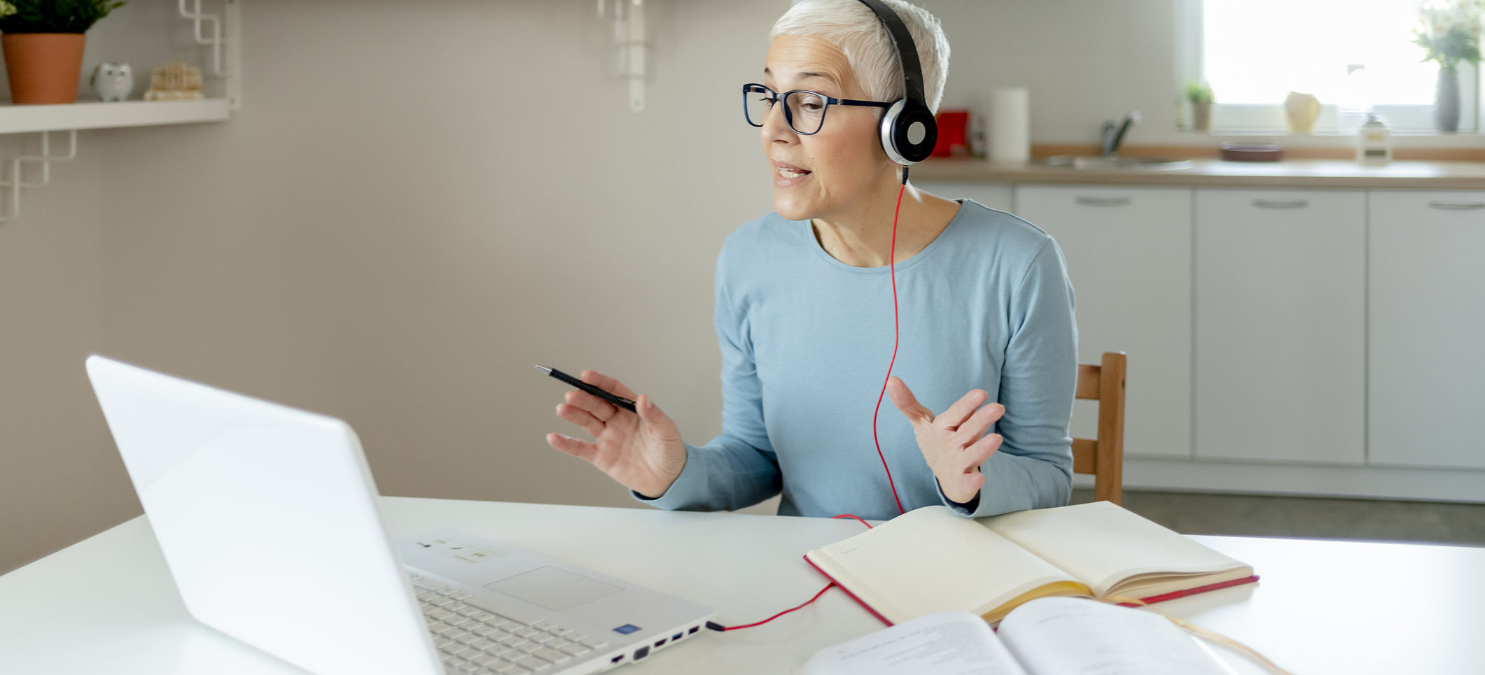 Photo of a woman with headphones on in a meeting at her laptop
