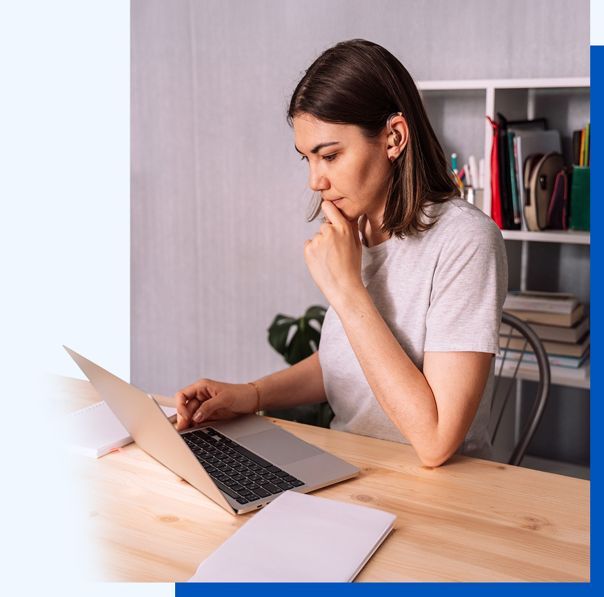 Photo of a woman sitting at a table working at a laptop