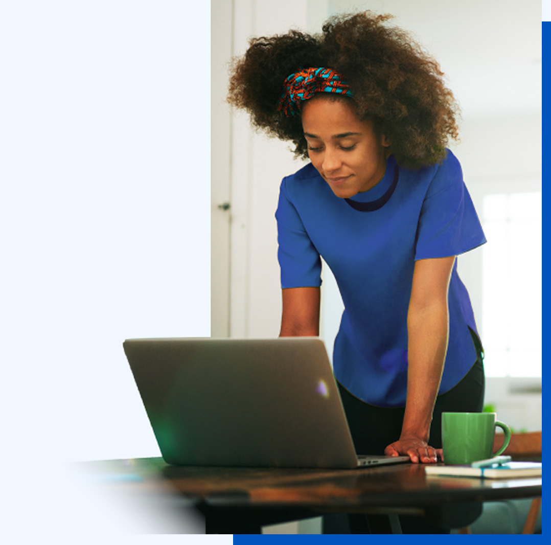 Stylized photo of a woman standing at a table looking at something on a laptop